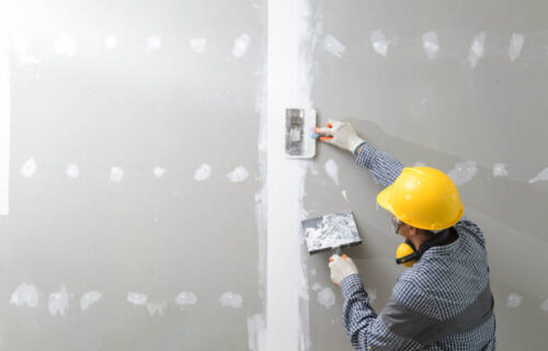 78 interior decoration construction furniture builtin.Plasterer in working uniform plastering the wall indoors.